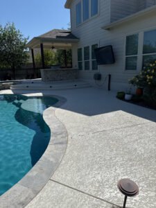 Backyard pool with patio and yellow flowers.