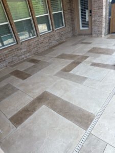 Patterned tile patio with brick walls and windows.