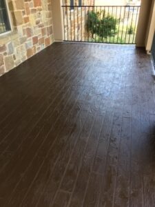 Stained concrete patio with stone wall and railing.