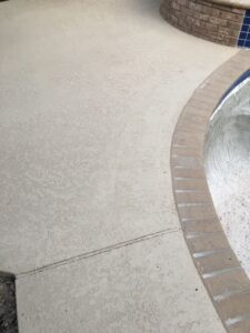 Textured concrete pool deck with brick edging.