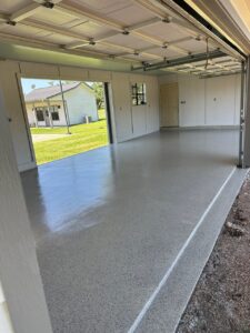 Finished garage with epoxy floor and open doors.