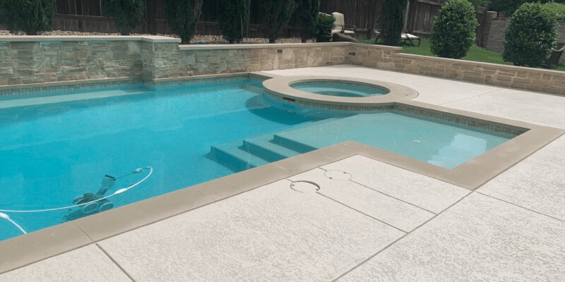 Backyard pool with attached spa and clean deck.