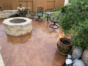Outdoor patio with stone fire pit and chairs.