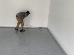 Person applying epoxy coating on garage floor