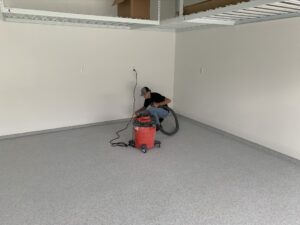 Man cleaning empty garage with vacuum cleaner.