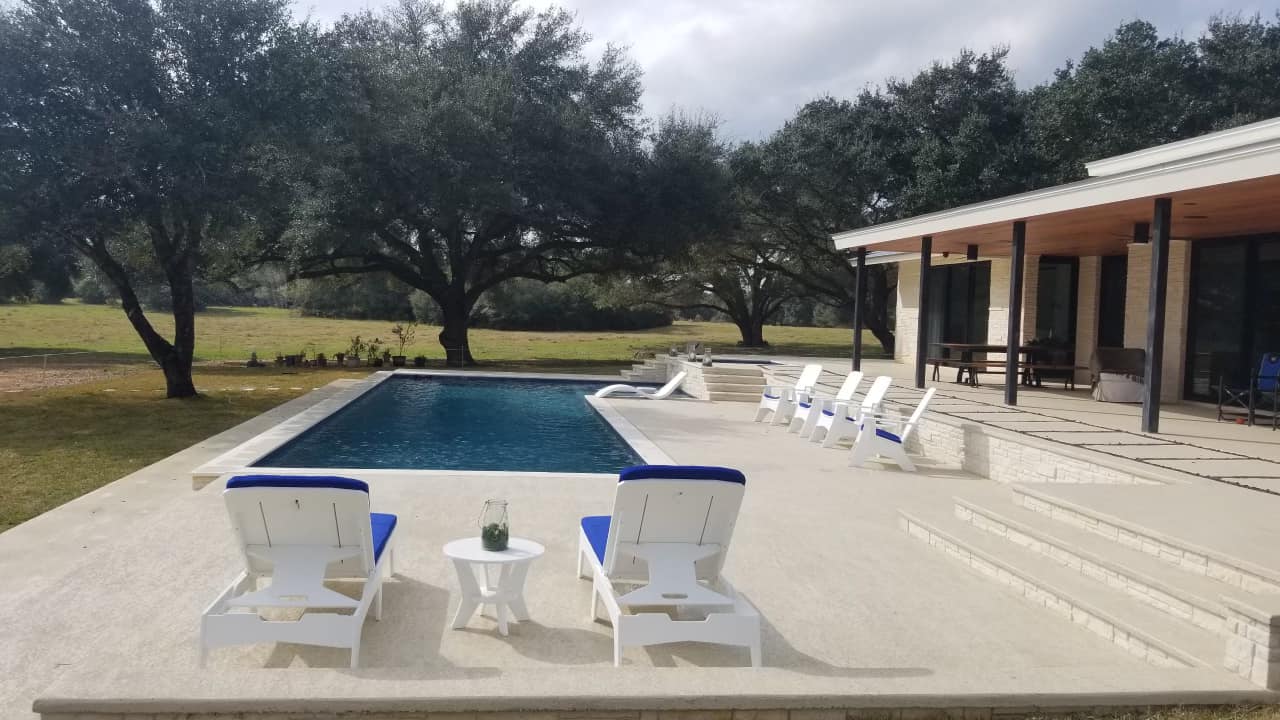 Modern house with pool and trees in background.