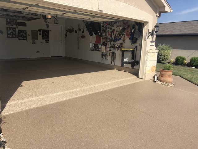 Open garage with tools and a driveway view.