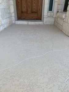 Textured concrete porch with wooden door entry.