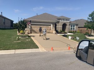 Two workers resurfacing home driveway with paint.