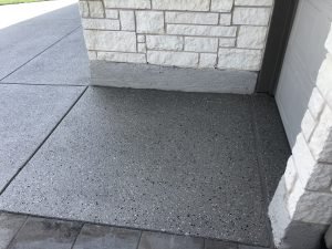 Textured concrete driveway near stone wall entrance.