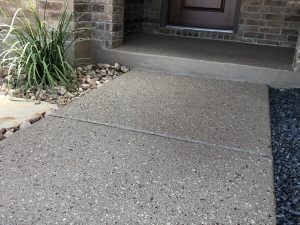 Concrete porch with grass and pebble accents