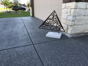 Metal sculpture on concrete driveway near garage