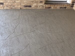 Textured concrete patio with brick wall background