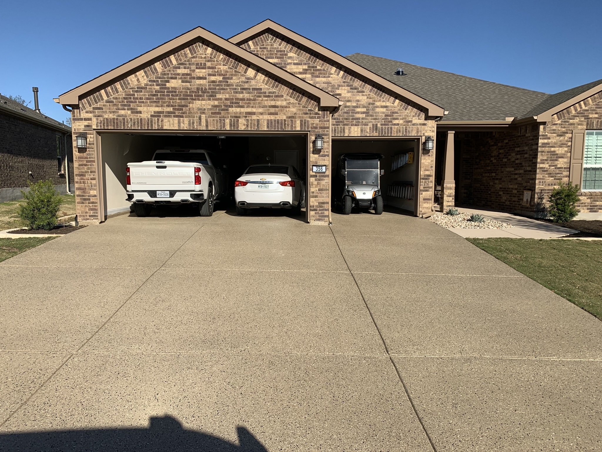 Three-car garage with parked vehicles in driveway.