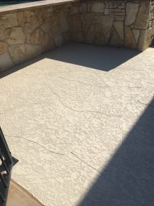 Textured concrete patio with stone wall background.