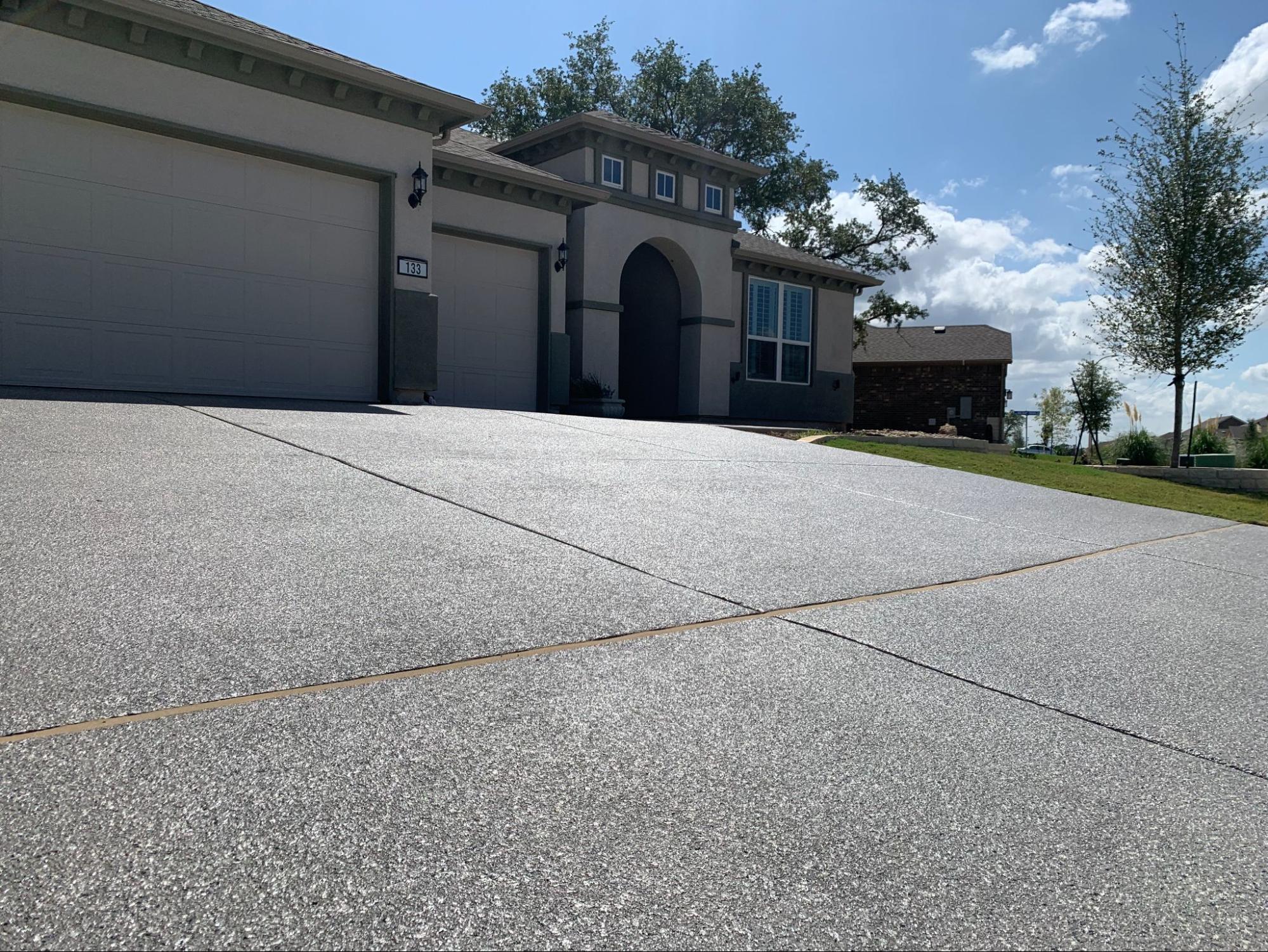 Sunny driveway leading to a suburban house.